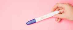 怀孕测试手粉红色的背景积极的测试怀孕复制空间