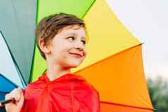 肖像笑学校男孩彩虹伞微笑孩子持有色彩鲜艳的伞肩膀快乐的孩子红色的雨衣持有多色伞