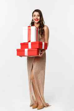 圣诞节聚会，派对庆祝活动概念全身的时尚的女人红色的嘴唇魅力衣服持有礼物微笑快乐站白色背景