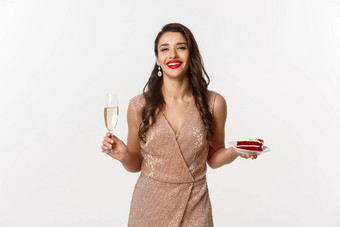 聚会，派对庆祝活动概念优雅的女人红色的嘴唇魅力衣服喝香槟吃蛋糕站白色背景