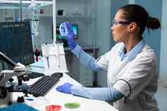 生物学家研究员女人持有透明的佩特里菜分析蓝色的解决方案