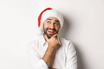 聚会，派对冬天假期庆祝活动概念特写镜头快乐男人。规划圣诞节礼物列表穿圣诞老人他上左角落里深思熟虑的白色背景