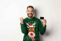 圣诞节假期购物概念兴奋男人。显示信贷卡快乐站白色背景
