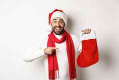 冬天假期庆祝活动概念兴奋男人。指出圣诞节袜子快乐收到一年礼物白色背景