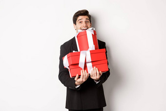 概念圣诞节假期庆祝活动生活方式图像快乐男人。西装携带礼物一年持有盒子礼物微笑站白色背景