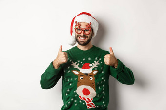 圣诞节假期庆祝活动概念快乐男人。圣诞老人他聚会，派对眼镜显示拇指批准站白色背景
