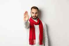 有胡子的的家伙显示停止标志拒绝标志禁止行动站冬天毛衣红色的围巾白色背景