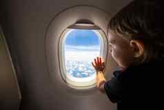可爱的蹒跚学步的点手指天空窗口飞行概念旅行孩子们
