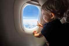 可爱的蹒跚学步的点手指天空窗口飞行概念旅行孩子们