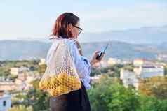 肖像中年女人智能手机趋势网格橙子在户外