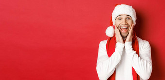 概念圣诞节冬天假期庆祝活动特写镜头惊讶快乐男人。圣诞老人他围巾令人惊异的站红色的背景