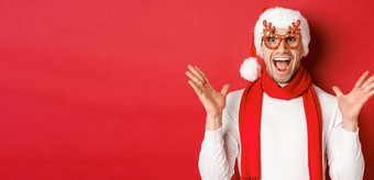 概念圣诞节冬天假期庆祝活动图像惊讶快乐男人。惊讶穿聚会，派对眼镜享受一年站红色的背景