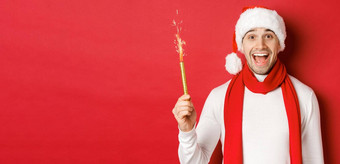 概念圣诞节冬天假期庆祝活动英俊的男人。庆祝一年有趣的持有炯炯有神的眼睛微笑穿圣诞老人他站红色的背景