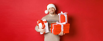 概念冬天假期一年庆祝活动肖像可爱的微笑男人。接收桩礼物持有礼物感动了惊喜站红色的背景感激的