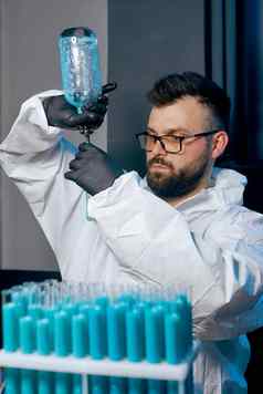 男人。科学家保护西装烧瓶蓝色的疫苗液体