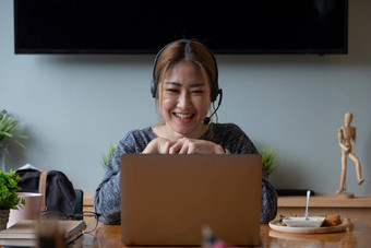 快乐亚洲女人自由职业者穿耳机沟通客户<strong>端</strong>视频<strong>电脑</strong>调用千禧愉快的专业女导师给在线语言类