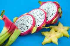 片龙水果火龙果粉红色的皮肤白色纸浆黑色的种子蓝色的背景异国情调的水果健康的吃概念