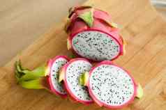 片龙水果火龙果粉红色的皮肤白色纸浆黑色的种子木减少董事会厨房异国情调的水果健康的吃概念