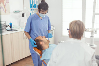 医疗护士使专业牙齿清洁男人。病人