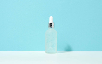 白色玻璃瓶吸管站蓝色的背景化妆品水疗中心品牌包装过来这里血清广告产品促销活动模拟