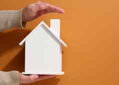 女手持有白色微型木房子棕色（的）背景真正的房地产保险概念环境保护家庭幸福