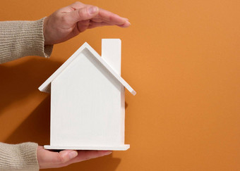 女手持有白色微型木房子棕色（的）背景真正的房地产保险概念环境保护家庭幸福