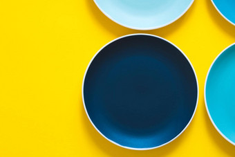 色彩斑斓的柔和的蓝色的陶<strong>瓷盘子</strong>孤立的黄色的背景