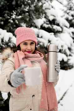 美丽的女人温暖的冬天衣服持有热水瓶喝热茶咖啡在户外雪一天