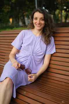 年轻的女孩光紫罗兰色的衣服伟大的时间假期夏天坐着板凳上旅行概念