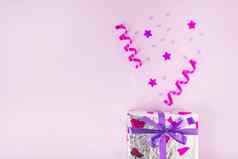 卷飘带明星形状五彩纸屑银礼物盒子粉红色的背景高质量照片