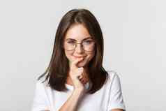 特写镜头深思熟虑的年轻的聪明的女孩眼镜微笑感兴趣选择产品思考白色背景