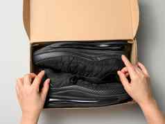 女手持有棕色（的）纸板盒子黑色的体育运动鞋灰色的表格检查在线订单