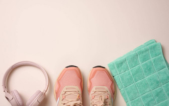 一对粉红色的纺织运动鞋无线耳机纺织绿色毛巾米色背景<strong>集体</strong>育运行