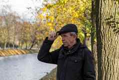 上了年纪的养老金领取者站美丽的秋天一天城市公园