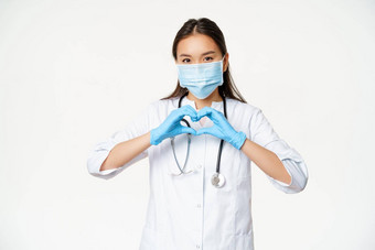 有爱心的亚洲医生女人医生医疗面具橡胶手套显示护理病人心标志白色背景