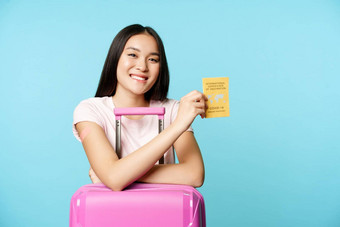 快乐微笑亚洲女孩旅游站可爱的手提箱机场显示国际科维德疫苗接种证书旅行者旅行安全疫苗接种蓝色的背景