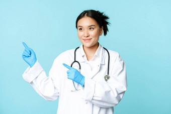 微笑亚洲医生医疗工人统一的指出左复制空间站蓝色的背景