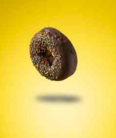巧克力甜甜圈五彩缤纷的洒悬浮黄色的背景