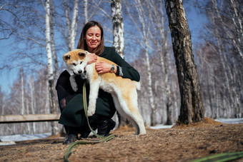 女人黑暗外套拥抱秋田<strong>犬犬</strong>儒小狗长绿色<strong>皮</strong>带秋天公园