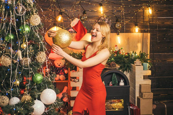 快乐的微笑金发女郎女人红色的衣服装修圣诞节树黄金球圣诞节时间圣诞节购物概念快乐假期圣诞节树一年惊喜现在