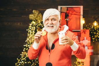 圣诞老人首页圣诞老人挑选饼干玻璃牛奶首页圣诞节胡子风格肖像圣诞老人老人喝牛奶玻璃持有饼干