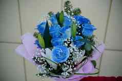 关闭女人的手持有色彩斑斓的花束花认不出来女持有花作文蓝色的玫瑰白色百合包装纸