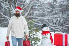 有趣的圣诞老人男人。摆姿势红色的礼物盒子冬天天气英俊的冬天男人。礼物雪人冷淡的冬天公园