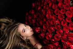 美丽的女人红色的玫瑰礼物爱美丽的微笑女孩持有大花束红色的玫瑰黑色的背景美丽的女人红色的玫瑰花束