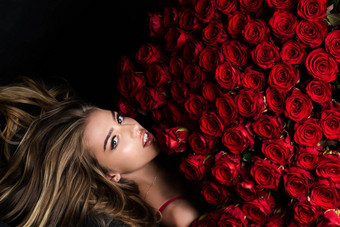 美丽的女人红色的玫瑰礼物爱美丽的微笑女孩持有大花束红色的玫瑰黑色的背景美丽的女人红色的玫瑰花束