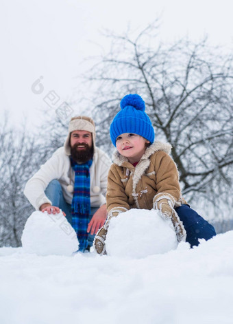 快乐父亲儿子使雪球雪手工制作的有趣的雪男人。快乐父亲儿子玩冬天圣诞节时间快乐冬天时间父亲儿子雪父亲一天