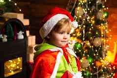 快乐孩子圣诞老人的他圣诞节树背景圣诞节时间男孩可爱的孩子快乐的情绪玩圣诞节树礼物冬天假期火的地方