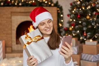 年轻的高加索人女人视频调用在线显示礼物盒子圣诞节一天聪明的电话首页社会距离女视频会议沟通假期