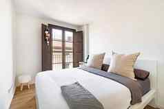 明亮的卧室舒适的床上大枕头窗口城市视图室内现代公寓欧洲城市