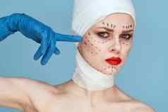 美丽的女人摆姿势蓝色的手套红色的嘴唇手术面部复兴孤立的背景